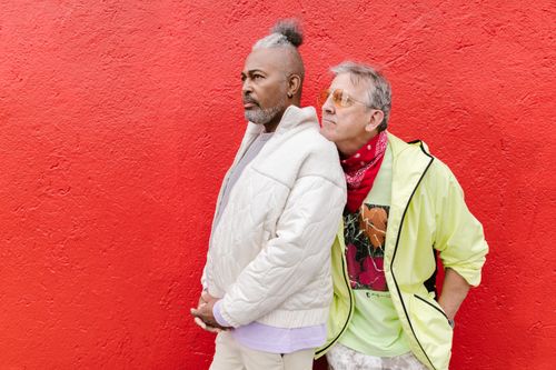 Free Two fashionable senior men standing against a vibrant red wall in casual outfits. Stock Photo