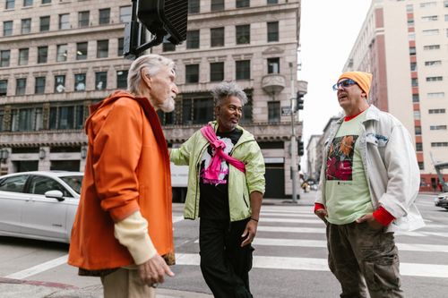 Free Three stylish men engaging in conversation at a city intersection, epitomizing urban friendship. Stock Photo
