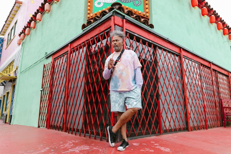 Fashionable Man Leaning On Red Folding Gate