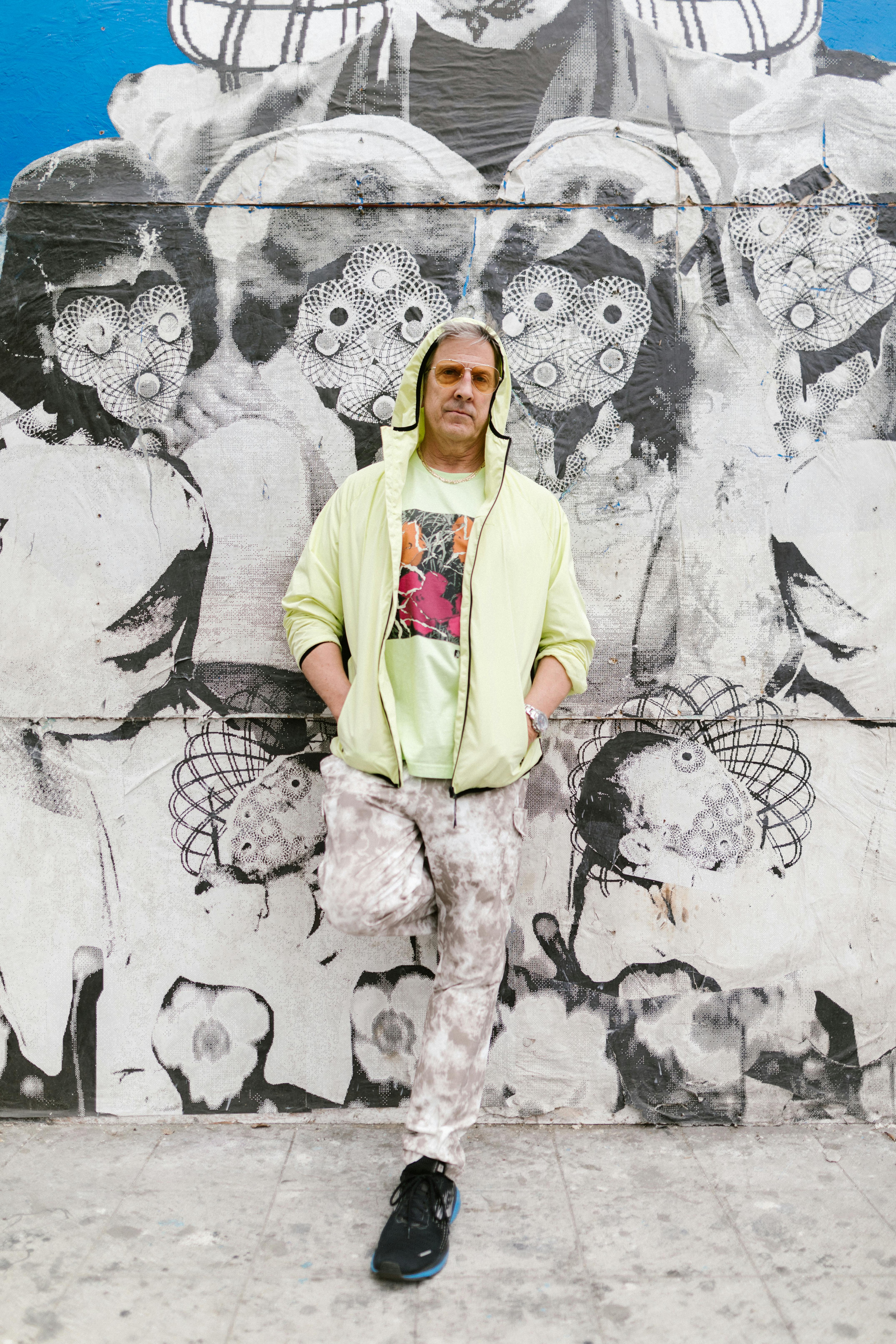 Hipster man in vibrant street fashion posing against a unique graffiti wall.