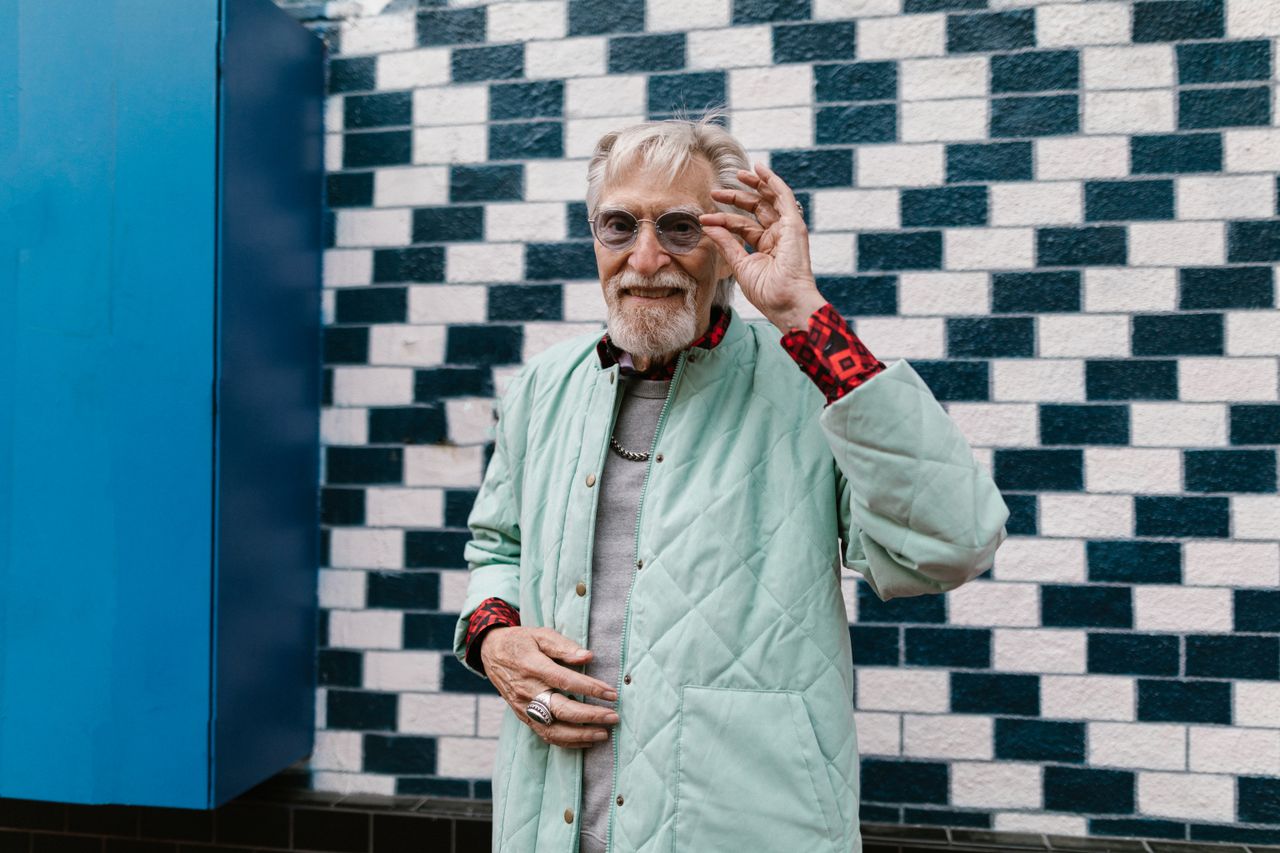 stylish senior man posing in fashionable streetwear against a brick wa