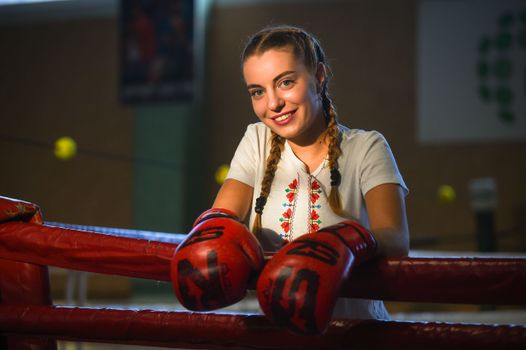 Confident woman with braids and boxing gloves inside a ring, showcasing empowerment.