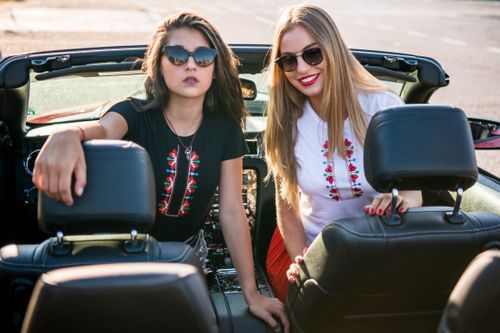 Free Two stylish women enjoy a sunny day in a convertible, embodying summer fun and fashion. Stock Photo