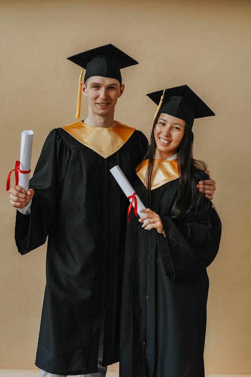 Free Woman in Black Academic Dress Holding Red and White Academic Hat Stock Photo