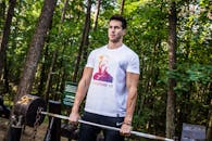 一名男子在森林公园举重，展示健身与力量