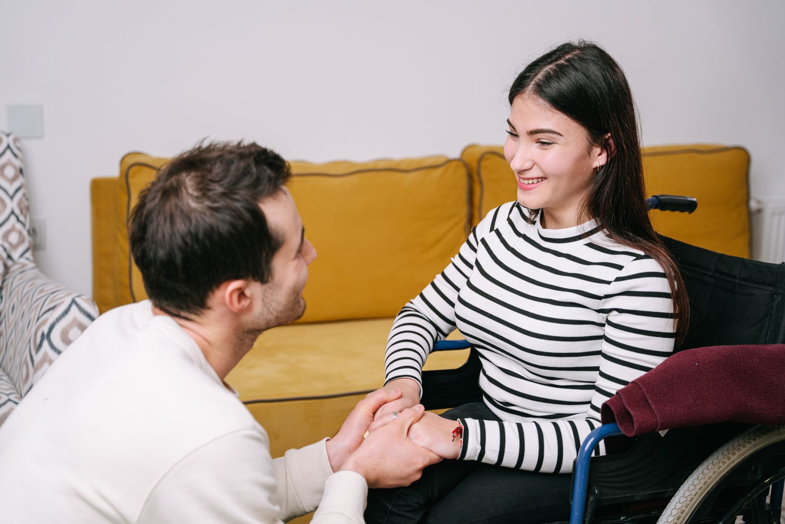 Two adults holding hands beside a sofa