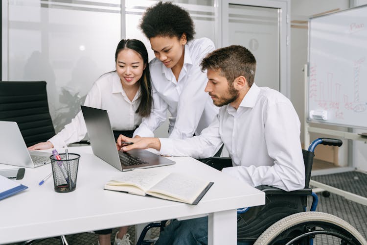 Coworkers Looking At A Laptop In An Office