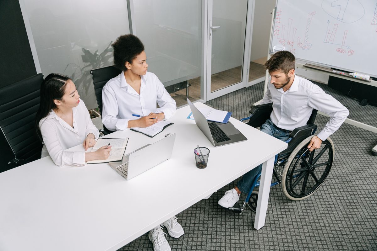 Manager meeting with two employees at a conference table to announce a business move and answer questions