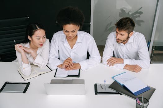 A diverse team collaborates in a modern office setting, focused on a laptop screen. Professional teamwork.