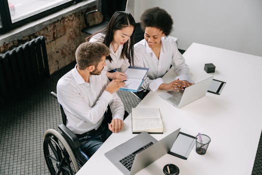 Three colleagues collaborating around a desk in an office space, showcasing diversity and teamwork.