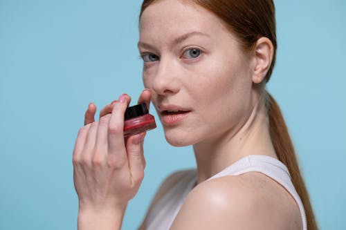 Woman Looking Sideways Holding Red Lipstick