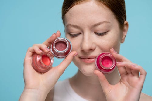 Woman Holding Glass Containers Of Lipstick With Different Shades