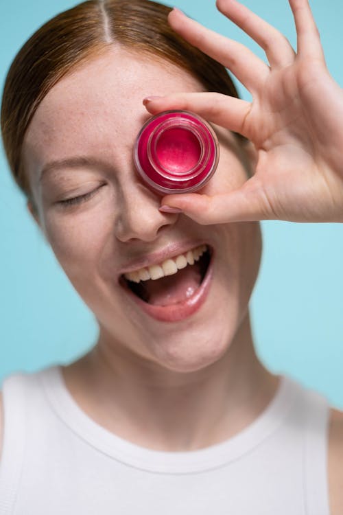 Smiling Woman Covering Her Eye With A Red Lipstick Cream