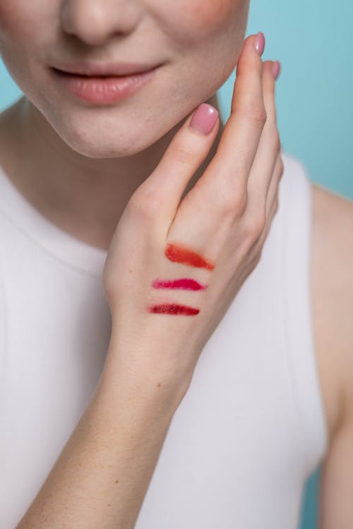 Free Woman in White Tank Top With  Different Shades Of Lipstick On Her Hand  Stock Photo