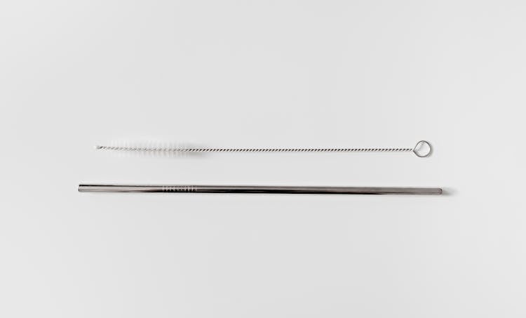 Photo Of A Metal Straw With Brush Against A White Background 