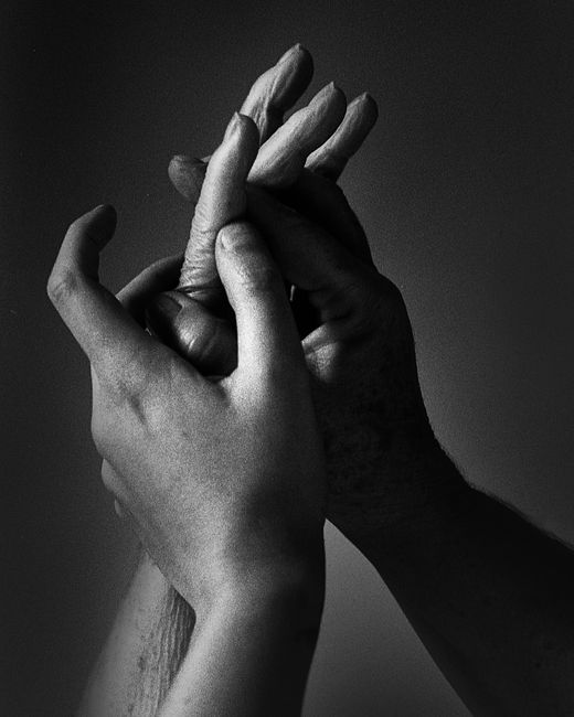 Close-up black and white image of two hands gently touching, conveying connection.