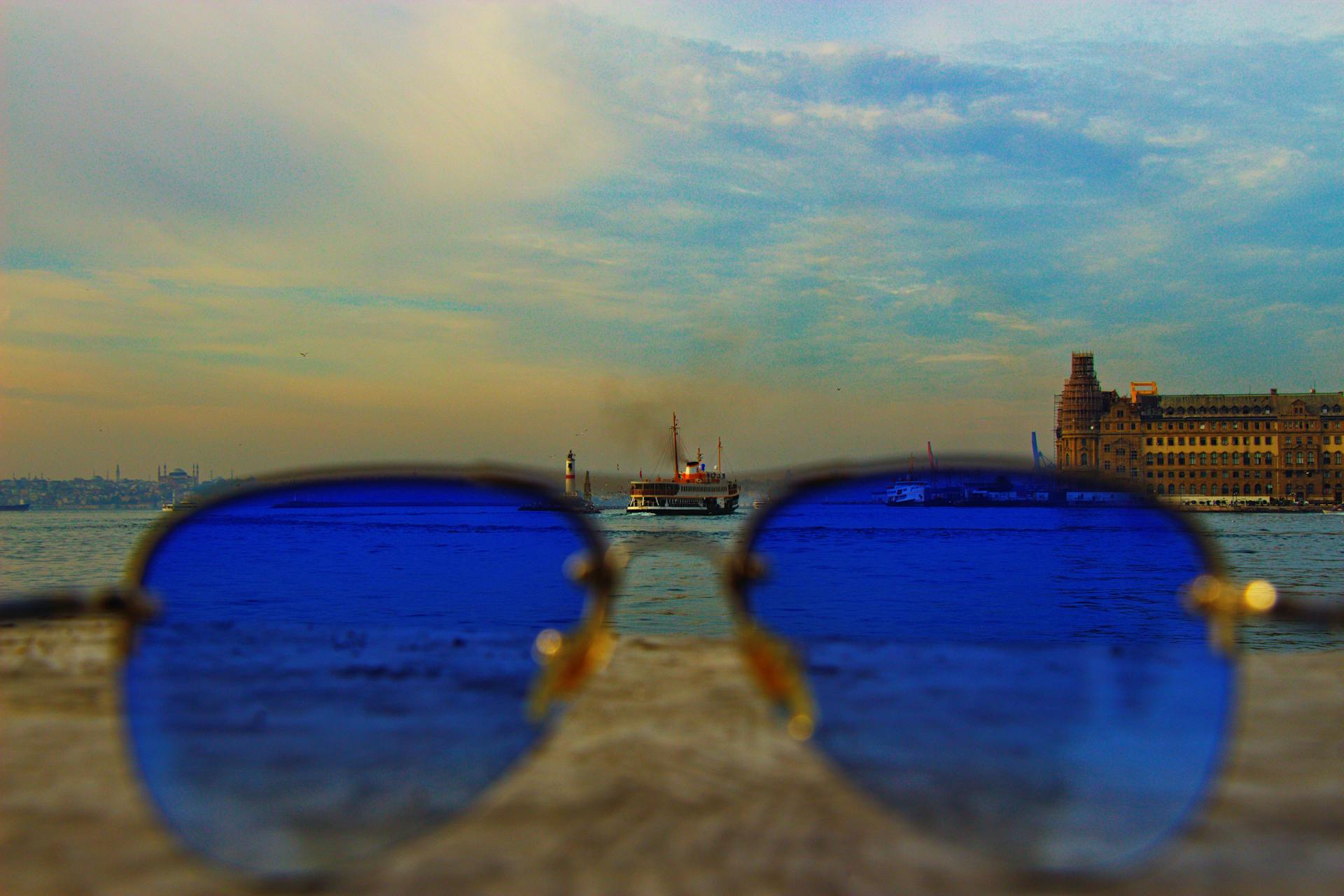 Sunglasses framing Istanbul's vivid sunset with historic architecture and ferry view.