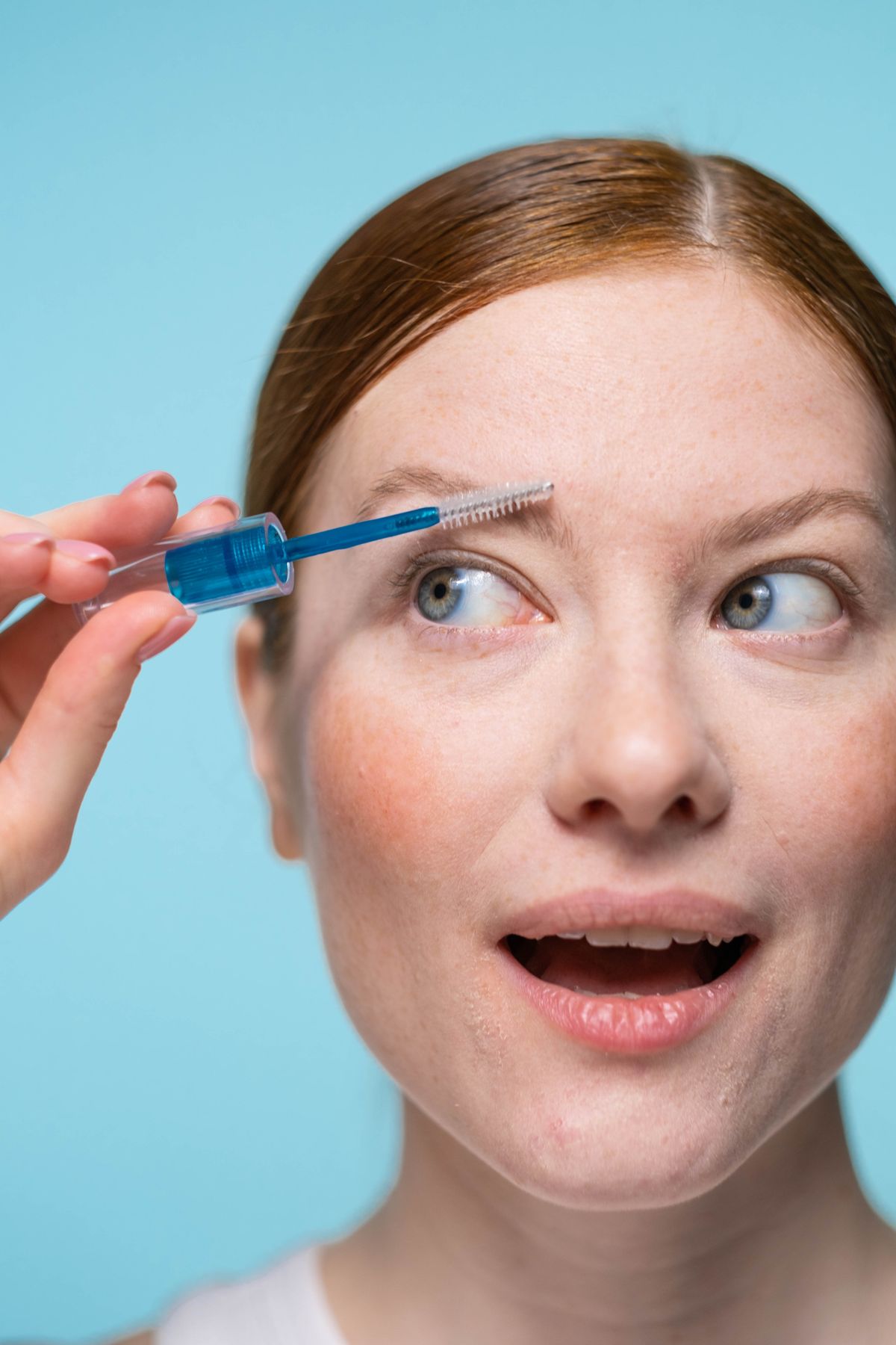 Close-up of a woman applying tinted eyebrow gel with a spoolie