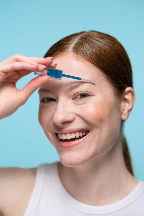Smiling Woman Applying An Eyebrow Makeup 