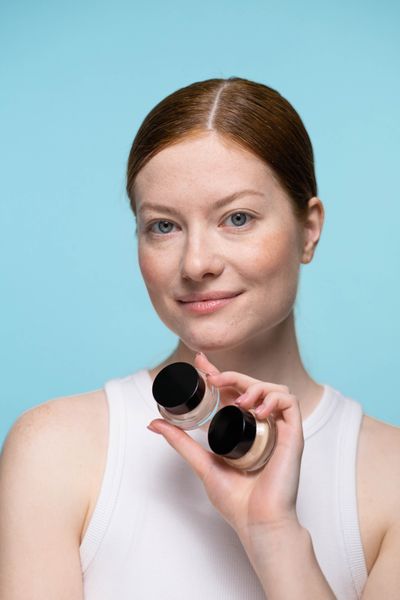 Portrait of a woman holding cosmetic products against a blue background — photo by Ron Lach on Pexels