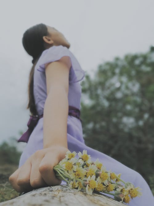 A Lady in Lilac Dress Holding a White Flowers