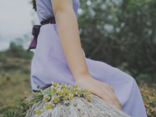 Person Sitting on a Wooden Surface near White Flowers