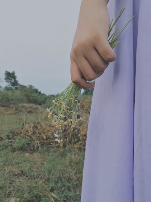Person in Purple Dress Holding Flowers
