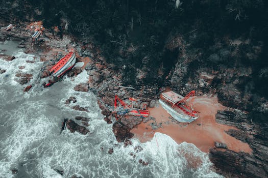 Aerial view of shipwrecks along the coastline of Chukai, Malaysia, surrounded by rocky cliffs and vibrant waves.