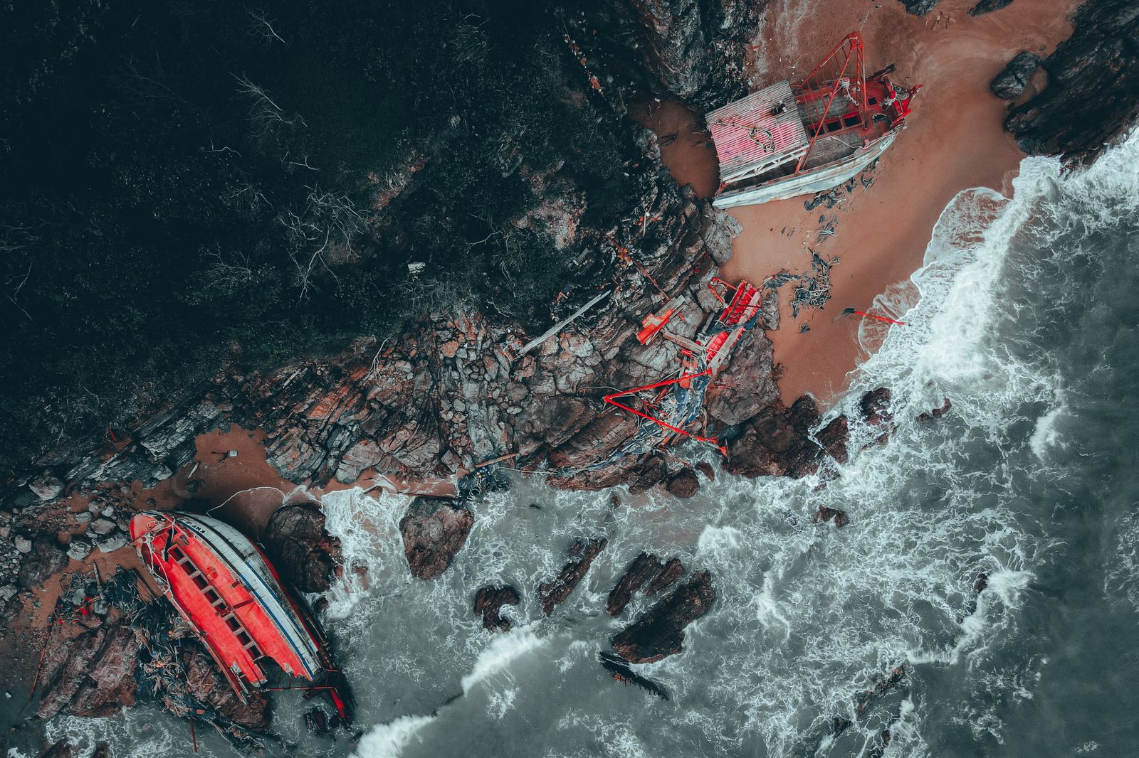Aerial view of a broken shipwreck on a rocky shore