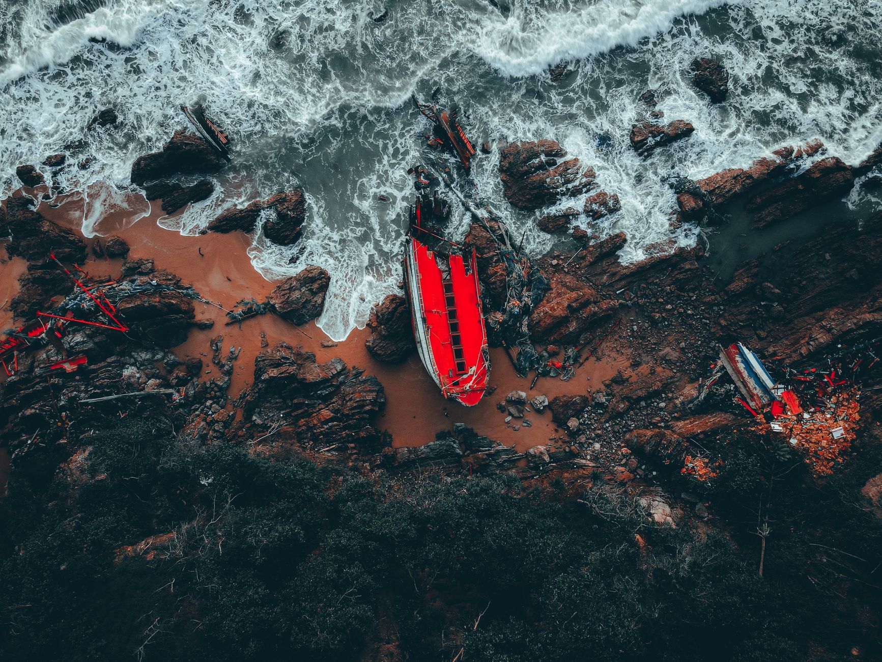 A dramatic aerial photograph of a shipwreck on the rugged coastline of Kemaman, Terengganu, Malaysia.