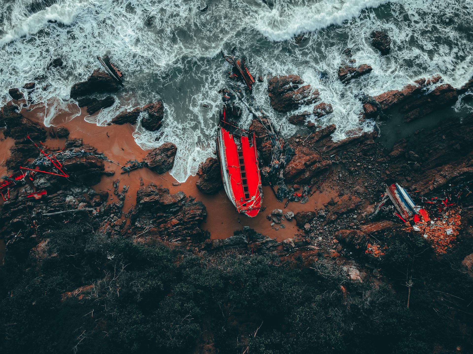A dramatic aerial photograph of a shipwreck on the rugged coastline of Kemaman, Terengganu, Malaysia.