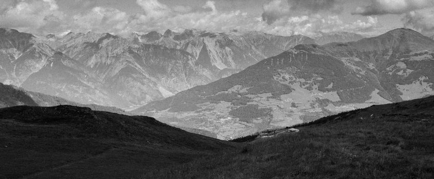 A scenic black and white view of a mountain range under cloudy skies.