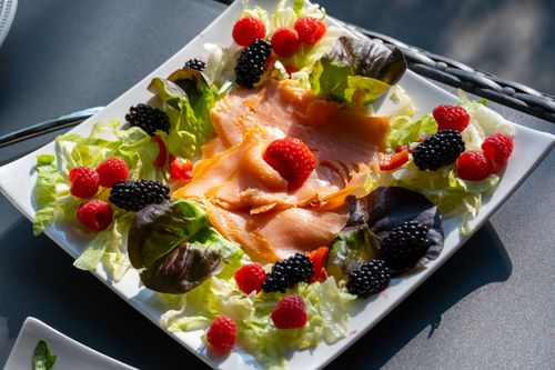 Free Delicious salmon and berry salad served on a plate, perfect for a healthy summer meal. Stock Photo
