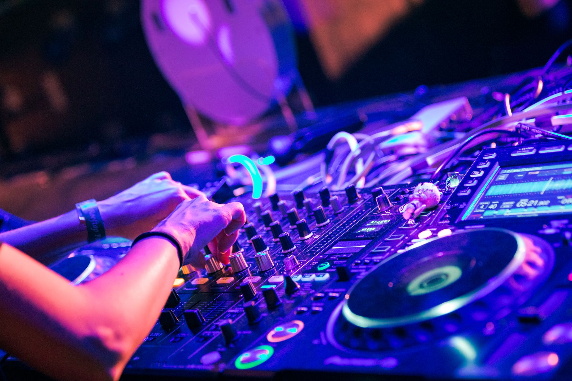 Bir DJ, gece kulübünde karıştırıcı masasında müzik çalıyor.