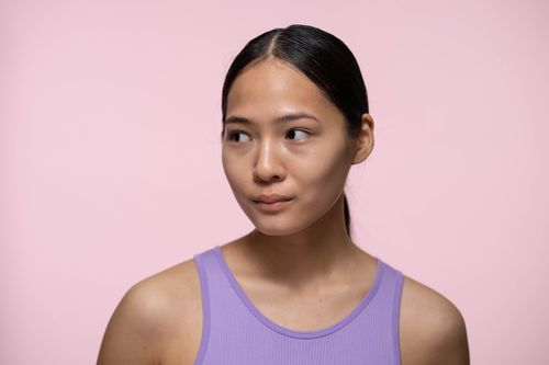 Free Close-up portrait of a woman with healthy skin and confident expression against a pink background. Stock Photo