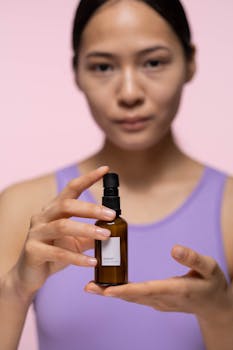 Focused close-up of a woman showcasing a skincare serum bottle.