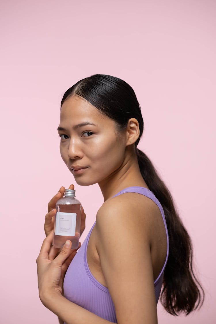 Woman In Purple Tank Top Holding Bottle Of Facial Tonic