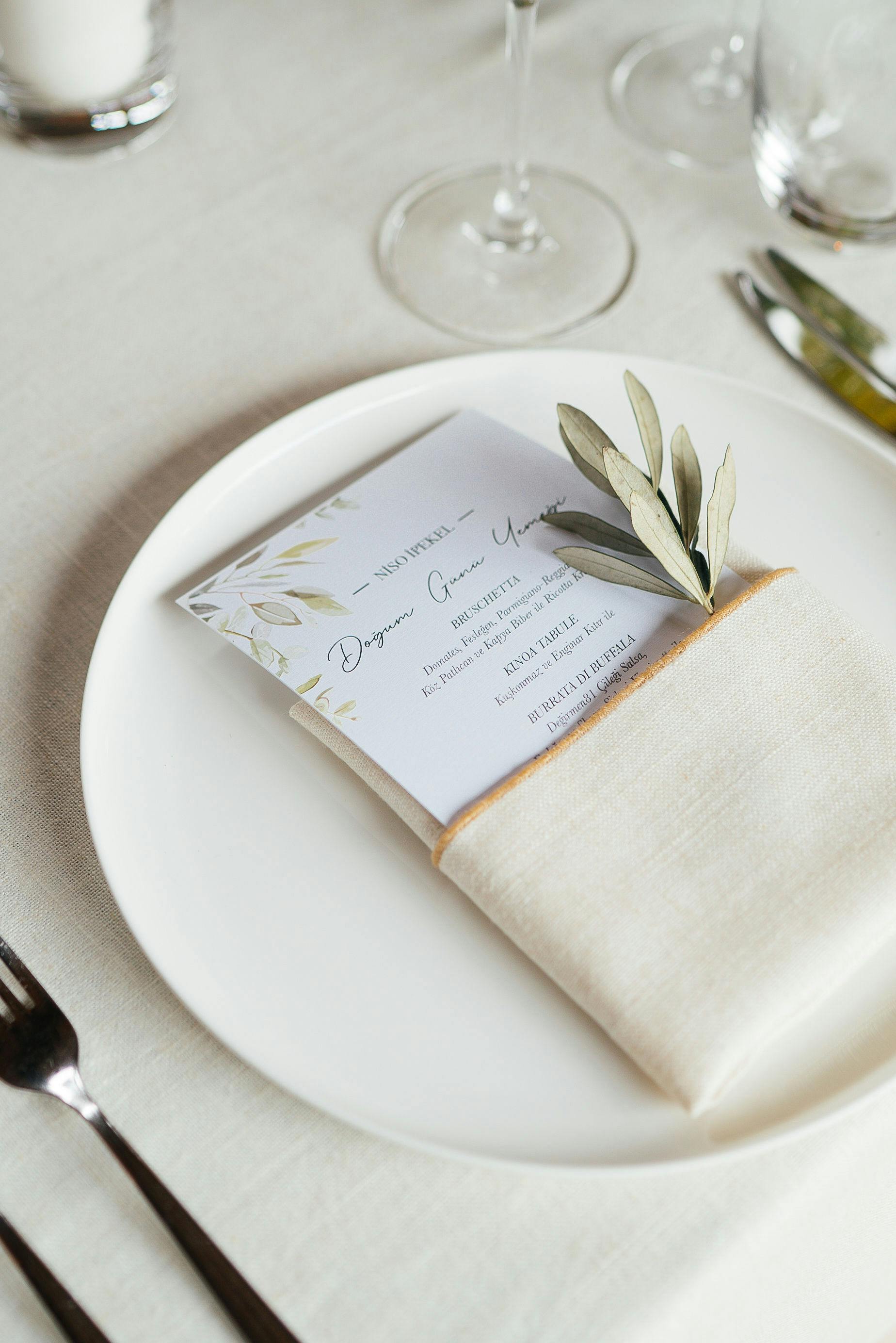 A sophisticated wedding place setting featuring a ceramic plate, napkin, and menu card.