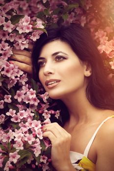 Portrait of an elegant woman posing amongst vibrant pink flowers, exuding grace and beauty.