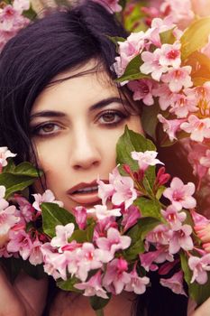 A captivating close-up of a woman enveloped by vibrant pink blossoms, exuding beauty and nature's elegance.