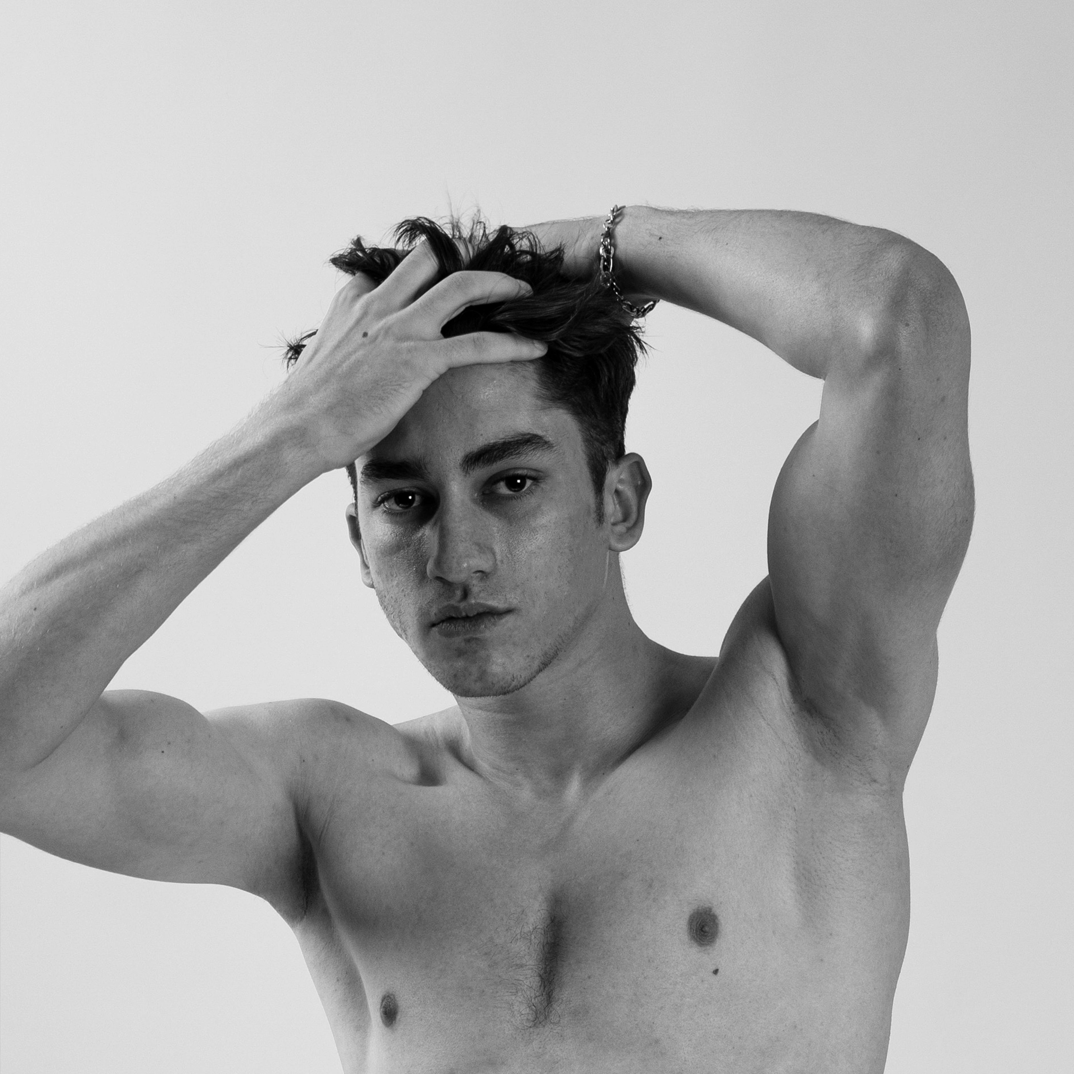 Self assured shirtless muscular man touching hair and looking at camera ·  Free Stock Photo