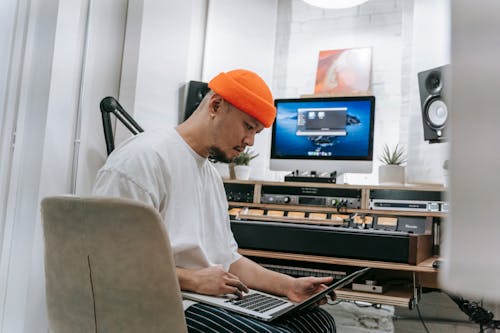 Man in White Shirt and Orange Hat Using Laptop