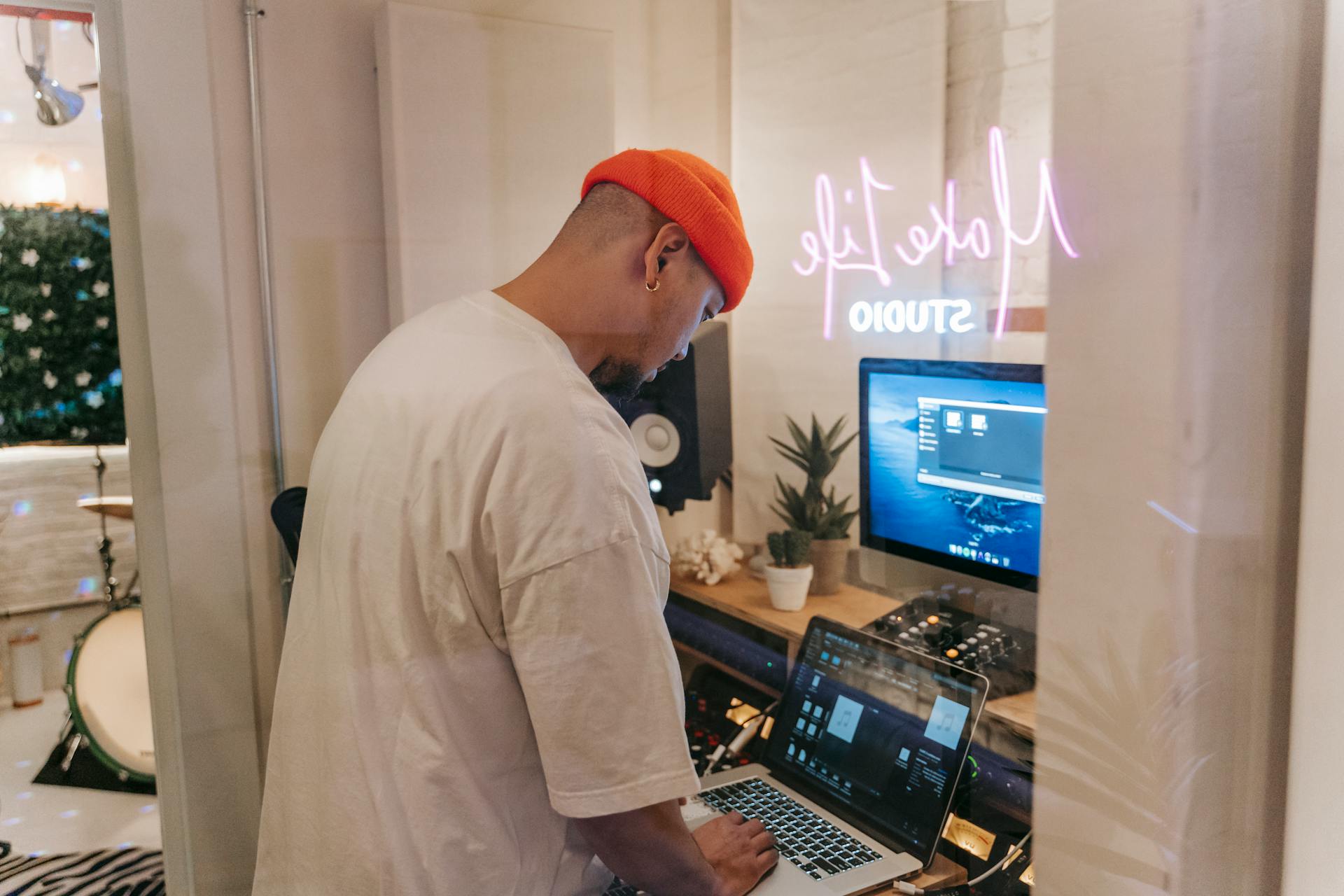 Man working on music production in a modern studio with laptop and equipment.