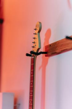 An elegant electric guitar hangs on a wall, beautifully lit with warm hues, creating a serene musical ambiance.