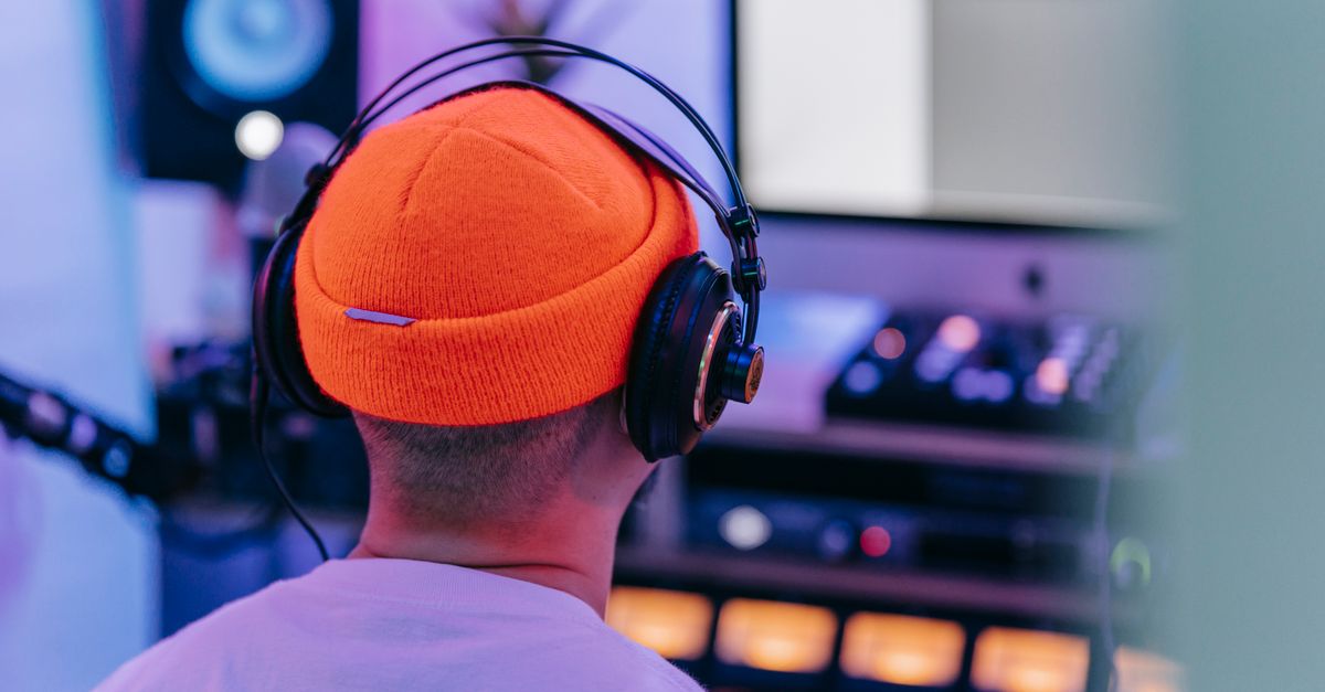 A music producer wearing headphones works intently in a vibrant studio environment.