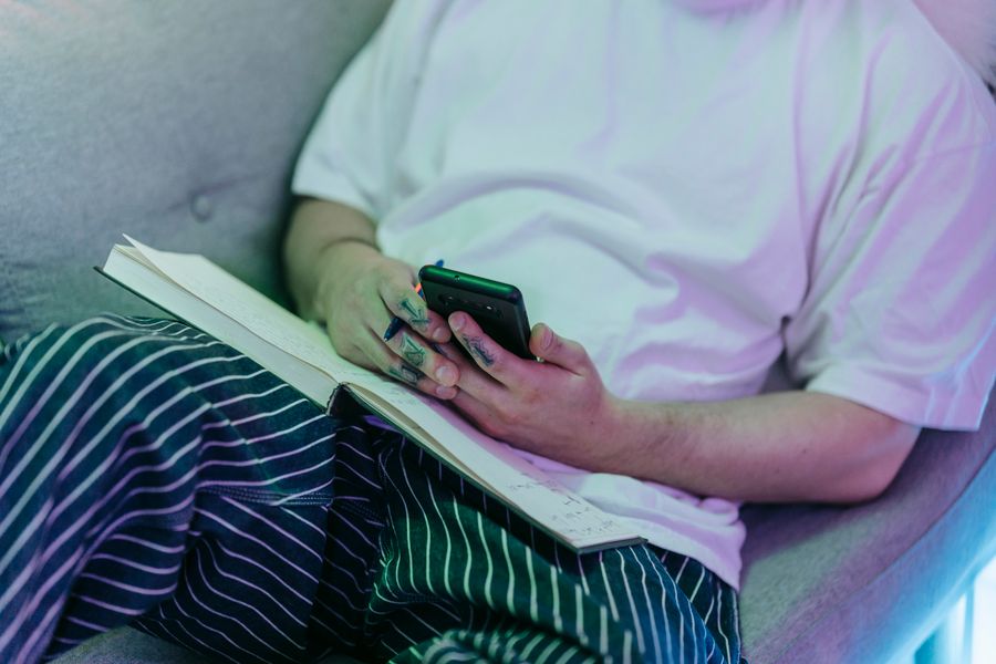 Person holding a smartphone with a notebook open on the table, managing a task
