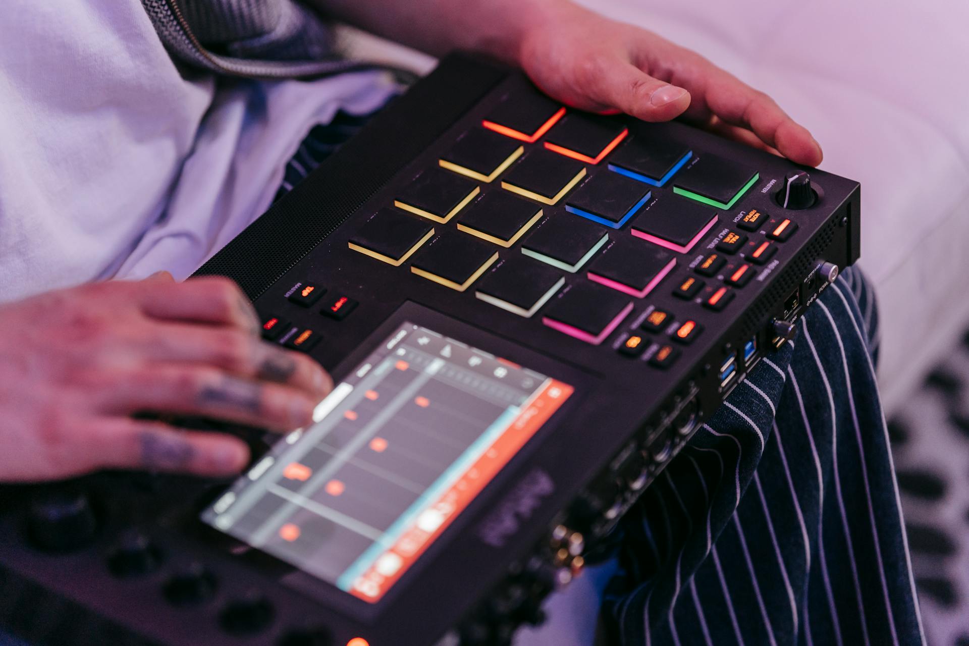 Hands operating a music sequencer for digital sound and beat creation.