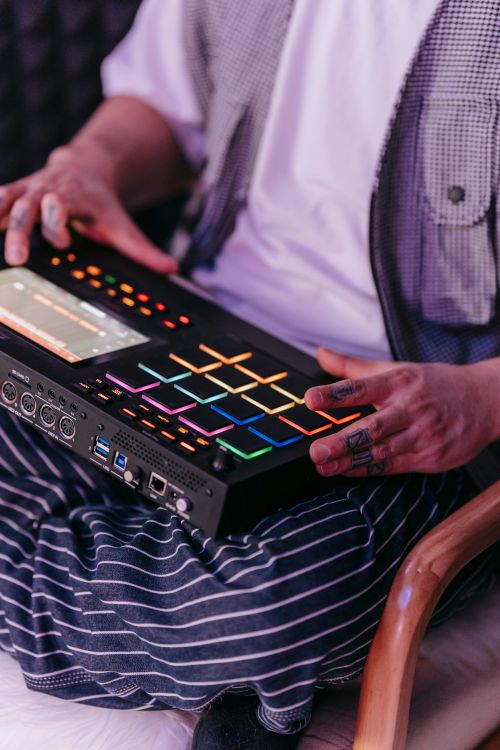 Free Close-up of a musician using an electronic music mixer, showcasing colorful buttons and creative expression. Stock Photo