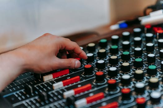 A close-up of a hand adjusting knobs on an audio mixer for precise sound control.