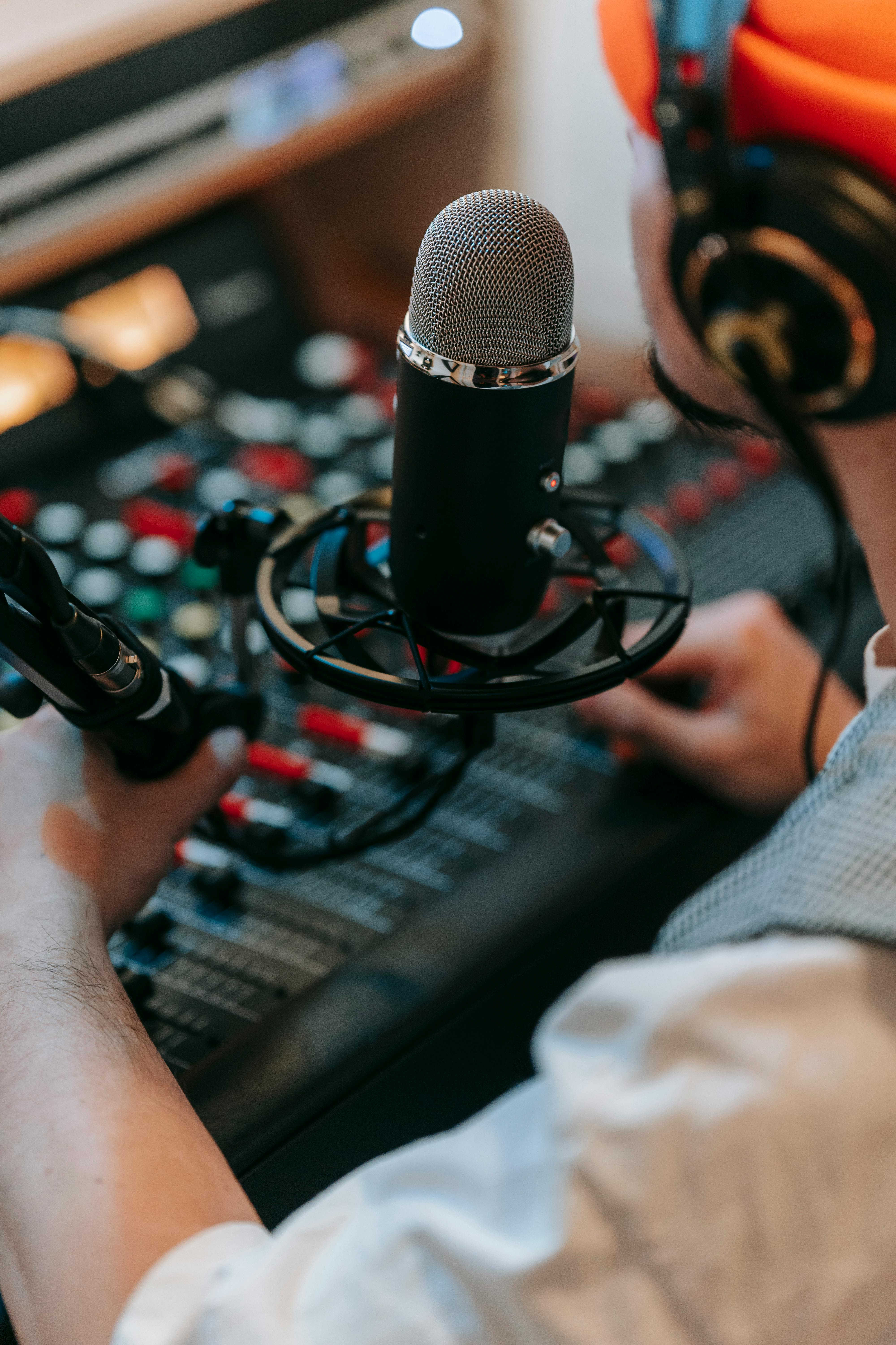 person in front of a microphone and audio mixer console